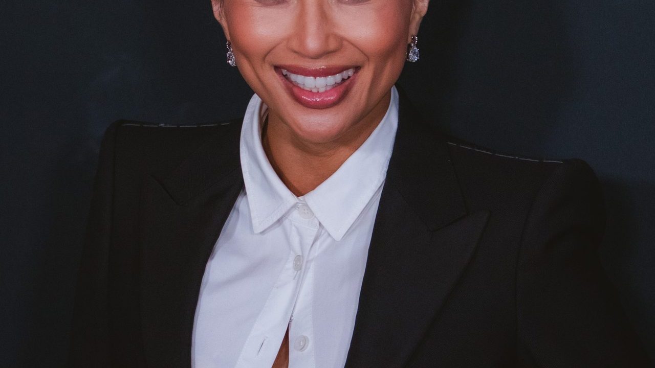 Jeannie Mai smiling at an event in a chic outfit
