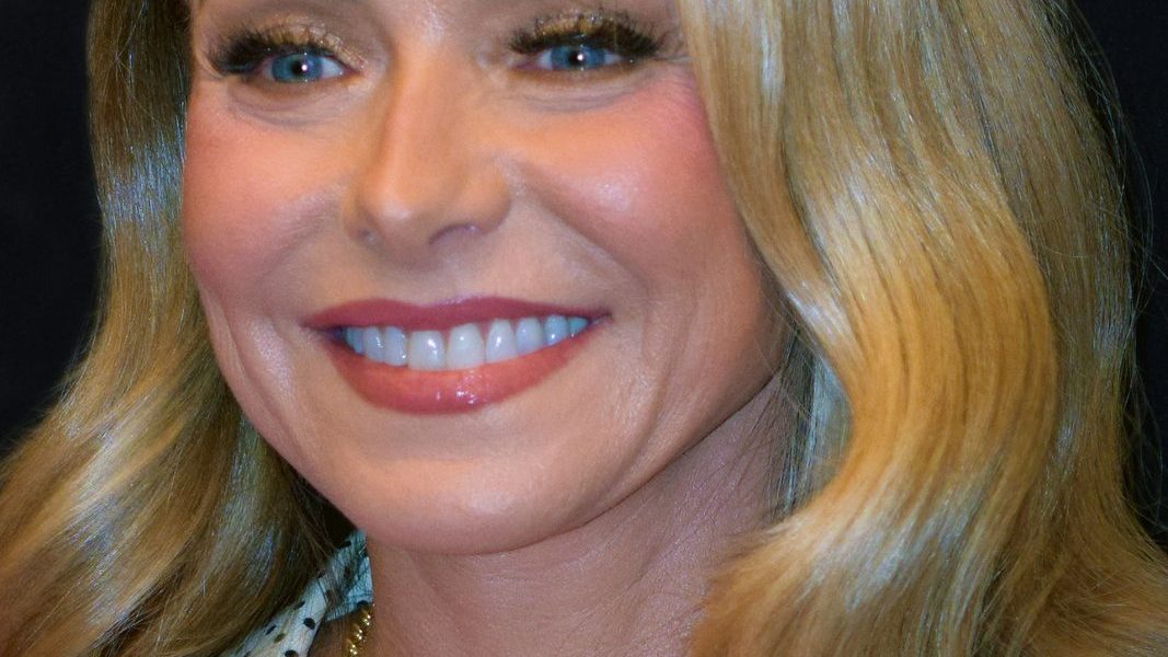 Kelly Ripa smiling at an event in a bright dress