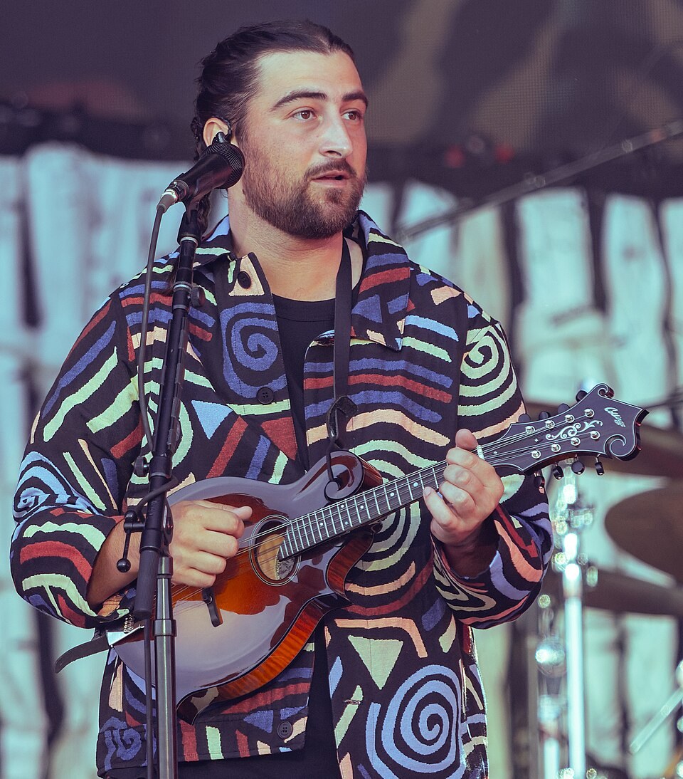 Noah Kahan performing on stage with his guitar