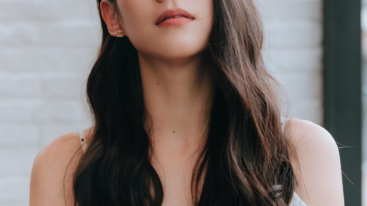 Arden Cho smiling at a film premiere in an elegant dress