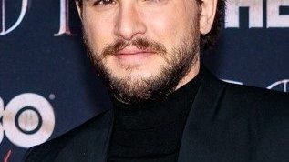 Kit Harington smiling at a premiere event in a dark suit